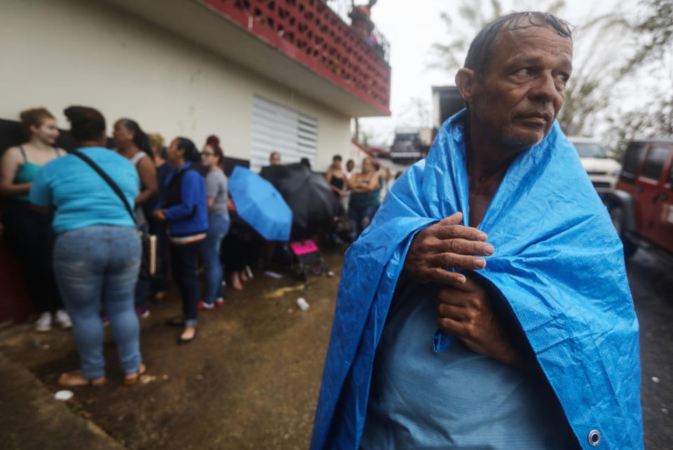 Arian Rodriguez covers himself in a tarp as residents of Juyuya wait in the rain for more than seven hours to register with FEMA. (Photo: Mario Tama via Getty Images)