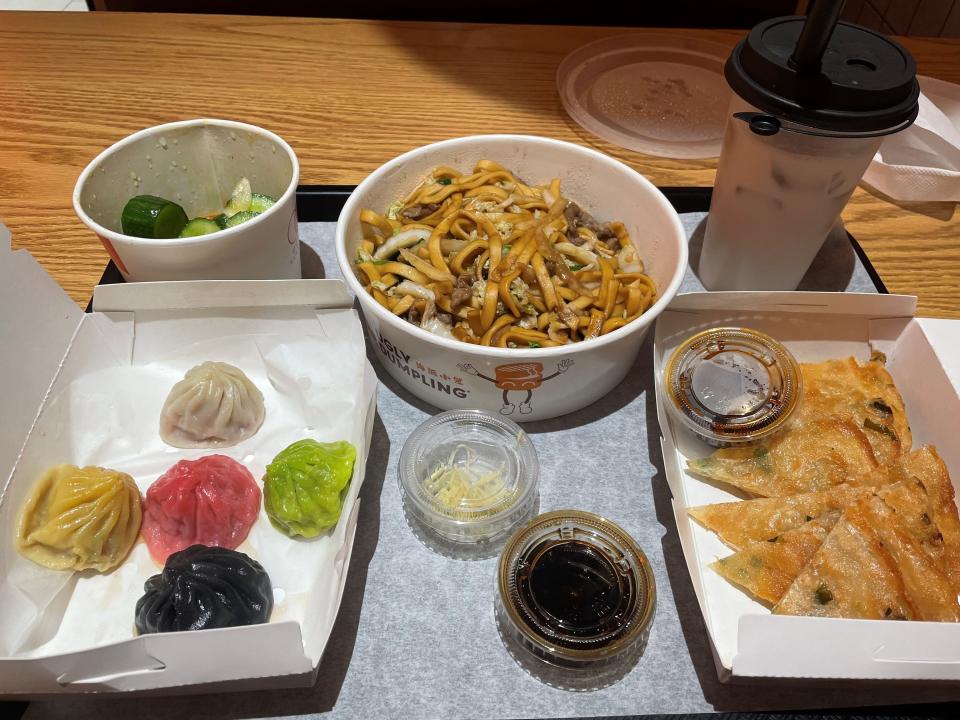 Dishes at Ugly Dumpling Express in Holmdel include (clockwise from bottom left) xiao long bao (soup dumplings), cucumber salad, stir-fried noodles with shredded beef, milk tea and scallion pancakes.