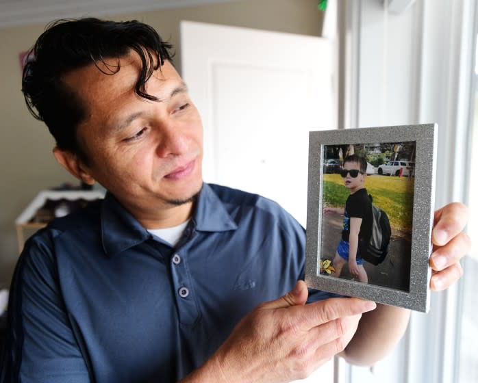 Carlos Rivera, holds up a photo of his son, Enrrique, 9, in his Surrey, BC, Canada, home May 6, 2021.