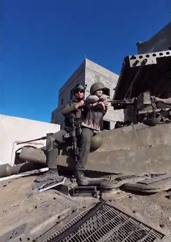 An Israeli soldier sits on top of a tank holding a female mannequin in a screengrab of a video