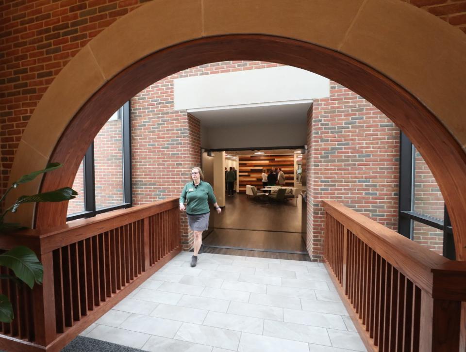 A Davey Tree Expert Company employee crosses the bridge through a glass atrium that connects the original build to the new building of its recently renovated headquarters and expanded facility in Kent.