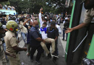 Indian policemen wearing face masks as a precaution against the coronavirus detain a protester during a protest against a pair of controversial agriculture bills in Bengaluru, India, Monday, Sept. 28, 2020. India's confirmed coronavirus tally has reached 6 million cases, keeping the country second to the United States in number of reported cases since the pandemic began. (AP Photo/Aijaz Rahi)