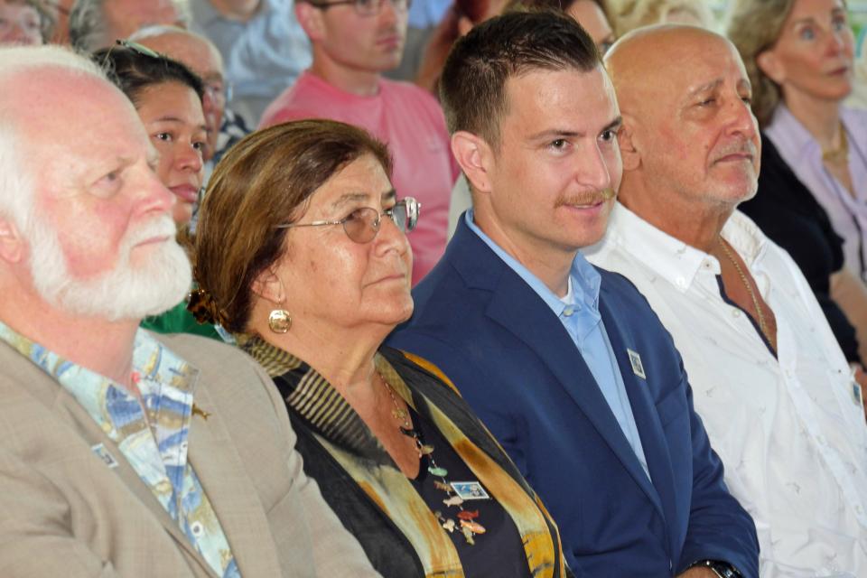 Pictured from left, Michael Crosby, president & CEO of Mote Marine Laboratory and Aquarium; Aya Konstantinou, daughter of Eugenie Clark; Eli Weiss, Clark’s son; and Tak Konstantinou, Clark’s son, listen to speakers Wednesday at the unveiling of the U.S. Postal Service Forever stamp honoring “Shark Lady” Eugenie Clark.