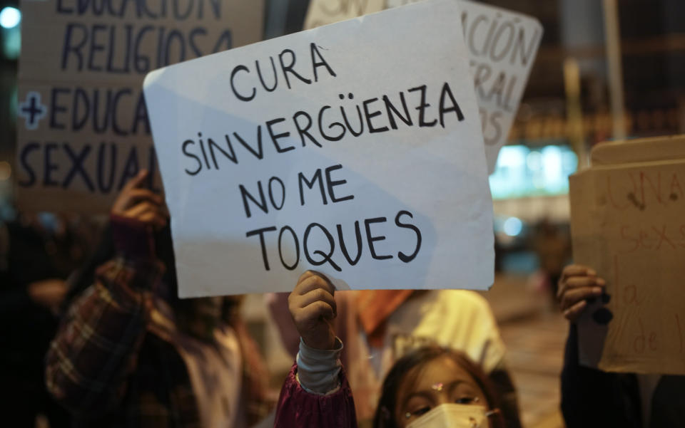 A girl holds a sign with a message that reads in Spanish "Shameless priest do not touch me" outside the offices of the Bolivian Episcopal Conference, in La Paz, Bolivia, Monday, May 15, 2023. Bolivia's Jesuit congregation has apologized publicly and is launching an investigation into a late Spanish priest who allegedly abused several minors in Bolivia dating back to the 1980s. (AP Photo/Juan Karita)