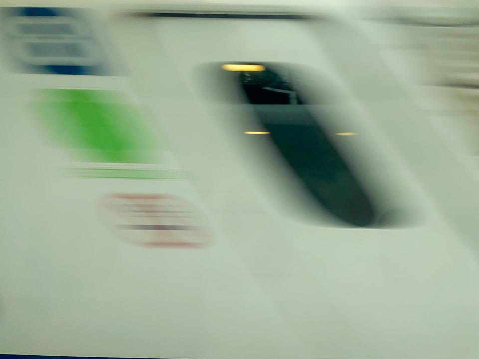 A blurry image of a train passing by while the author rides a bullet train.