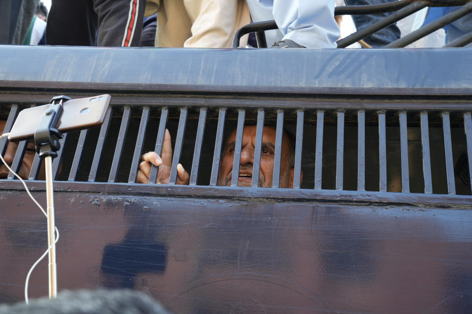 Azam Swati, a senior leader of Pakistan's former prime minister Imran Khan's 'Pakistan Tehreek-e-Insaf' party talks with media inside from a police van during a rally, in Lahore, Pakistan, Wednesday, Feb. 22, 2023. Hundreds of supporters of Pakistan's former prime minister on Wednesday defied a ban on rallies in a commercial area of the city of Lahore, taunting police and asking to be arrested en masse. (AP Photo/K.M. Chaudary)