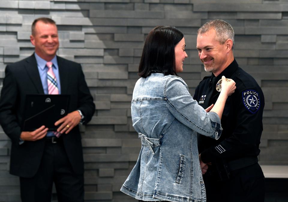 Shannon Milliorn pins on her husband Chris' new lieutenant badge as Abilene Police Chief Ron Serrate looks on Wednesday.