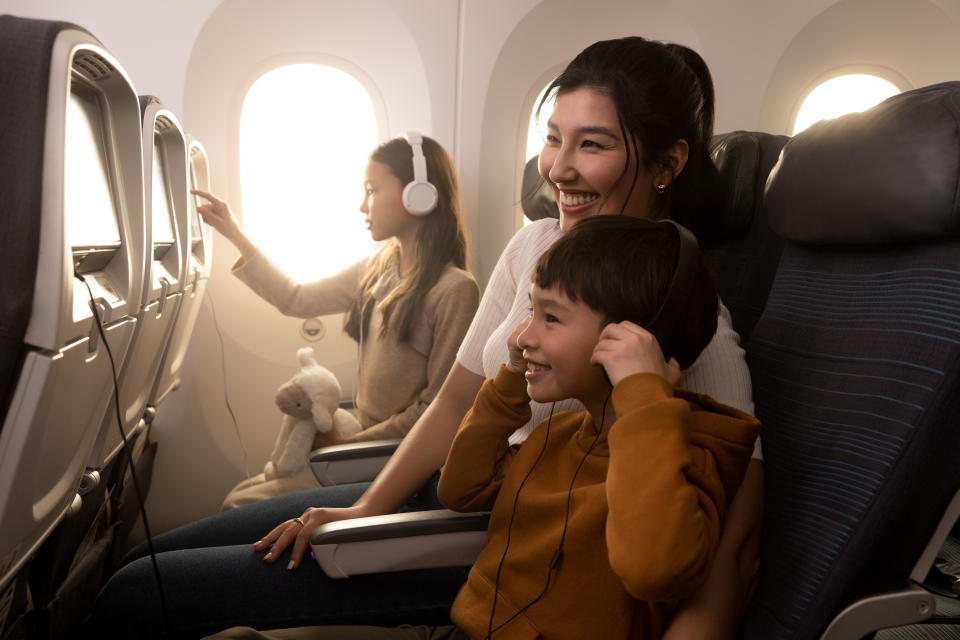 A woman and her two children enjoy Air Canada on flight entertainment