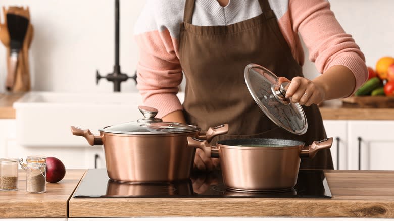 Person removing lid from copper pot