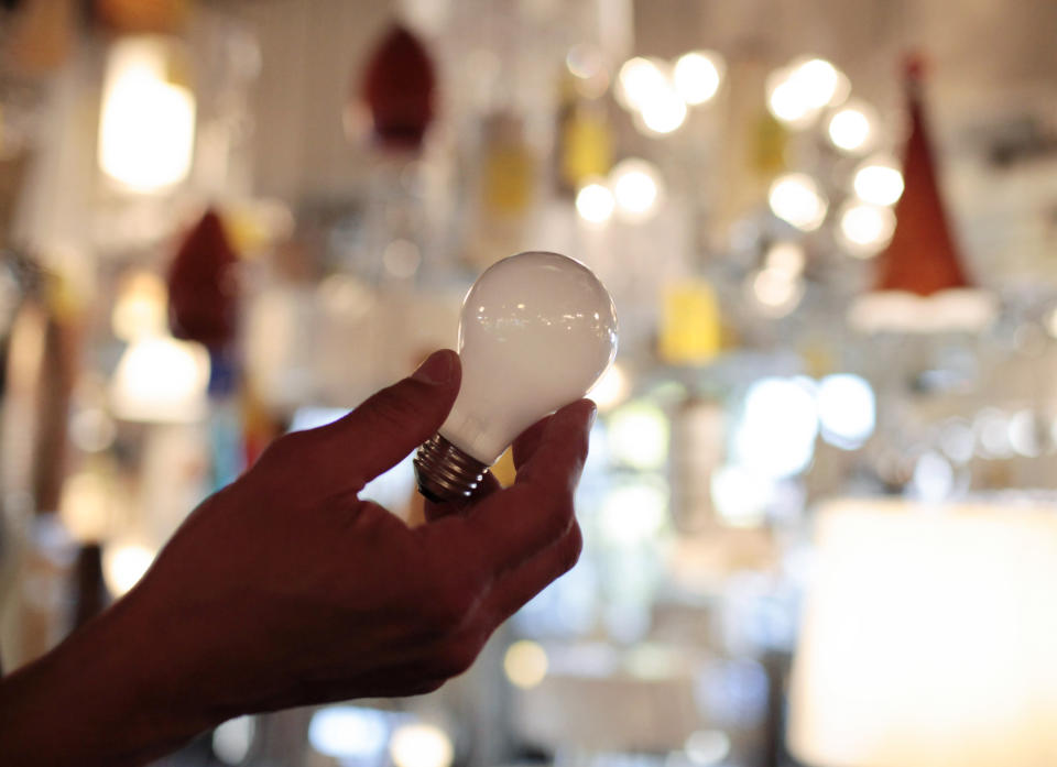 FILE - Manager Nick Reynoza holds a 100-watt incandescent light bulb at Royal Lighting in Los Angeles, Jan. 21, 2011. The Biden administration is scrapping old-fashioned incandescent light bulbs, speeding an ongoing trend toward more efficient lighting that officials say will save households, schools and businesses billion of dollars a year. (AP Photo/Jae C. Hong, File)