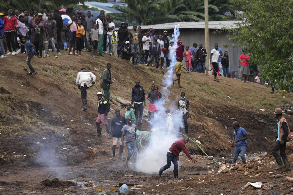 Residents throw back teargas at riot police as excavators and bulldozers bring down their homes in the Mathare area of Nairobi, Kenya Wednesday, May. 8, 2024. The Kenyan government ordered the evacuation of people from flood-prone areas, resulting in the demolition of houses and the loss of at least one life in the melee caused by the forced evictions. (AP Photo/Brian Inganga)