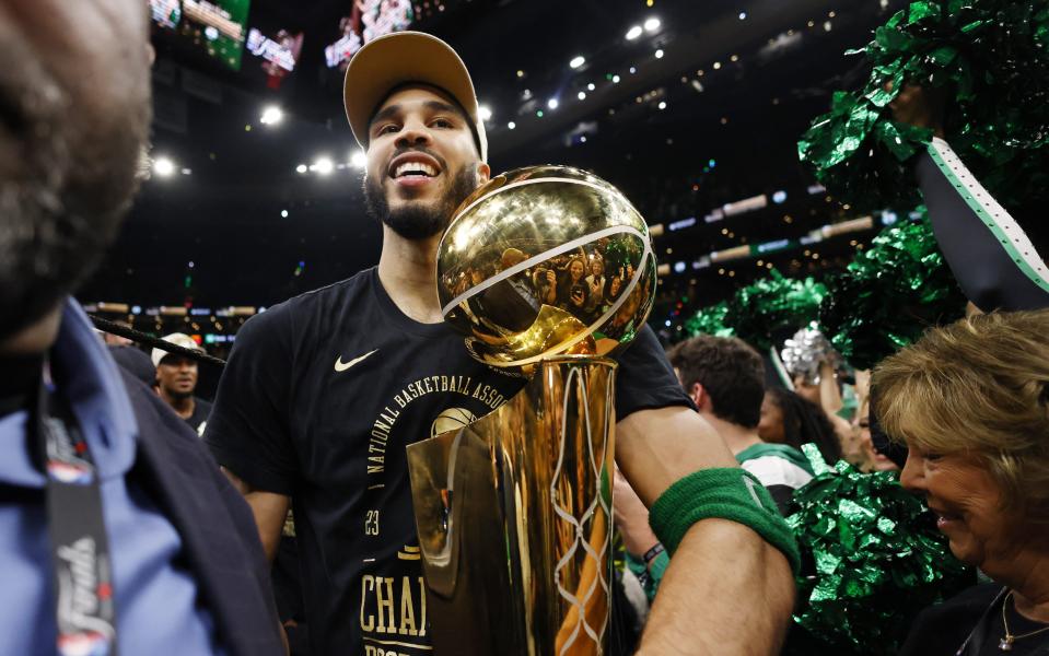 Jun 17, 2024; Boston, Massachusetts, USA; Boston Celtics forward Jayson Tatum (0) walks off the court with the trophy as he celebrates winning the 2024 NBA Finals against the Dallas Mavericks at TD Garden. Mandatory Credit: Peter Casey-USA TODAY Sports