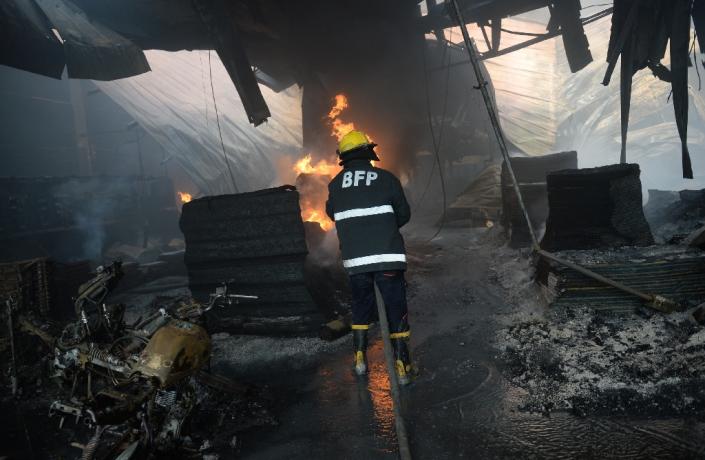 Philippine fire fighters try to put out a blaze at a footwear factory in the Valenzuela district on the edge of Manila on May 13, 2015 (AFP Photo/Ted Aljibe)
