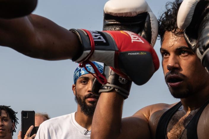 Dwayne Taylor ,center, of Lincoln Park, watches as a punch is thrown while he referees a Pick Your Poison Detroit event in Detroit&#39;s Delray neighborhood on Sunday, August 8, 2021.