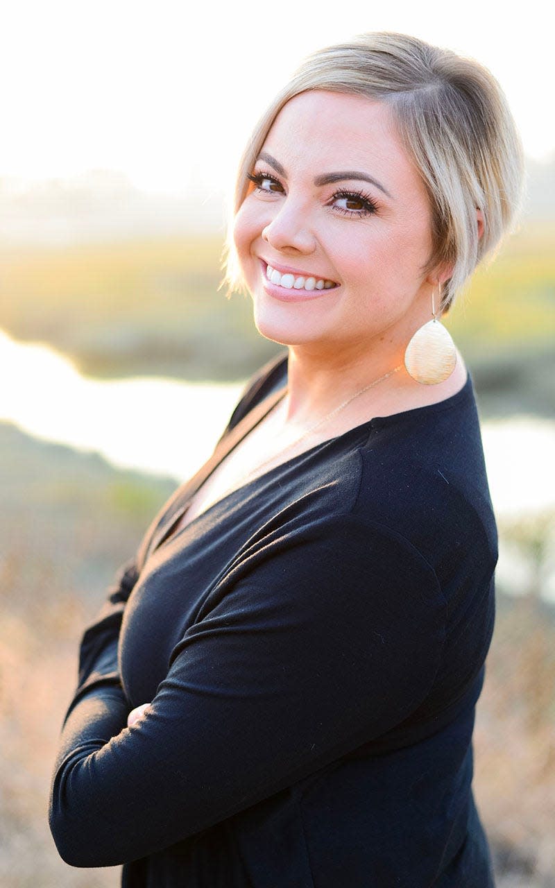 Amanda C. Riley with blonde hair and a Black shirt smiling.