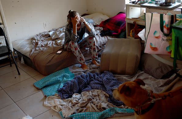 FORT MYERS, FLORIDA - SEPTEMBER 30: Val Stuart talks on a cell phone as she sits on the bed she setup on the floor after the apartment she was staying in was flooded when Hurricane Ian passed through the area on September 30, 2022 in Fort Myers, Florida.  Mrs. Stuart who evacuated from Sanibel before the storm ended up staying in the apartment and had to flee in the middle of the storm through a window because of flood waters to a second floor apartment.  The hurricane brought high winds, storm surges and rain to the area causing severe damage. (Photo by Joe Raedle/Getty Images)