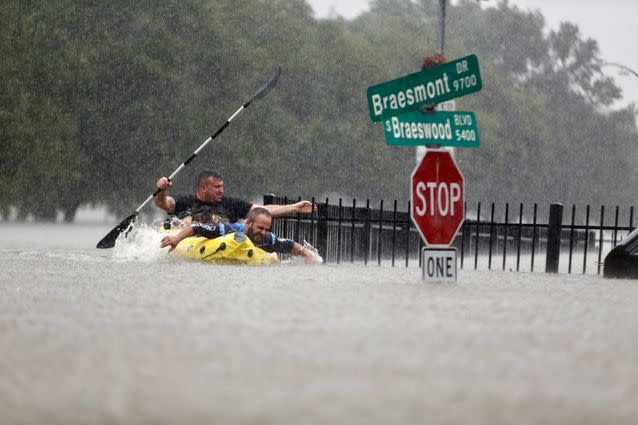 Men paddle to safety in torrential rains in Texas, brought by ex-Hurricane Harvey. Source: AP