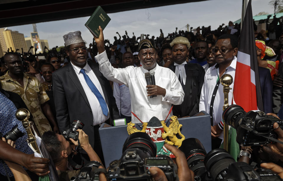 <p>Opposition leader Raila Odinga holds a bible aloft after swearing an oath during a mock “swearing-in” ceremony at Uhuru Park in downtown Nairobi, Kenya Tuesday, Jan. 30, 2018. (Photo: Ben Curtis/AP) </p>