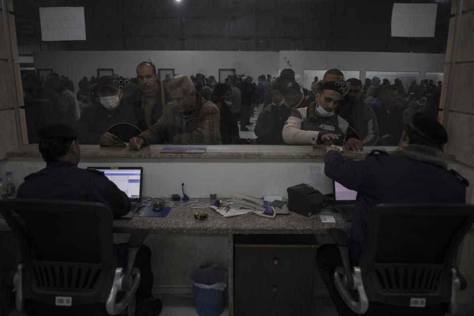 Hamas police officers check the documents of workers at the Palestinian side of Erez crossing before heading to Israel, in the town of Beit Hanoun, northern Gaza Strip, March. 27, 2022. Israel said it will reopen its crossing with the Gaza Strip to Palestinian workers on Tuesday, April 26, 2022, after it had been closed for several days following rocket attacks from the Palestinian enclave. Israel has issued thousands of work permits to Palestinians from Gaza, which has been under a crippling Israeli and Egyptian blockade since Hamas seized power from rival Palestinian forces nearly 15 years ago. (AP Photo/Khalil Hamra)