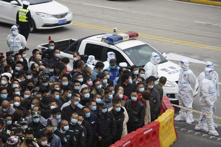 Security workers in protective suits stand by as workers wearing face masks to help curb the spread of the coronavirus gather for COVID-19 testing at the Shanghai Pudong International Airport in Shanghai, Monday, Nov. 23, 2020. Chinese authorities are testing millions of people, imposing lockdowns and shutting down schools after multiple locally transmitted coronavirus cases were discovered in three cities across the country last week. (AP Photo)