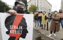 Women's rights and man activists with posters of the Women's Strike action protest against recent tightening of Poland's restrictive abortion law in front of the parliament building as inside, guards had to be used to shield right-wing ruling party leader Jaroslaw Kaczynski from angry opposition lawmakers, in Warsaw, Poland, on Tuesday, Oct. 27, 2020. Massive nationwide protests have been held ever since a top court ruled Thursday that abortions due to fetal congenital defects are unconstitutional. Slogan reads 'Women’s Strike'. (AP Photo/Czarek Sokolowski)