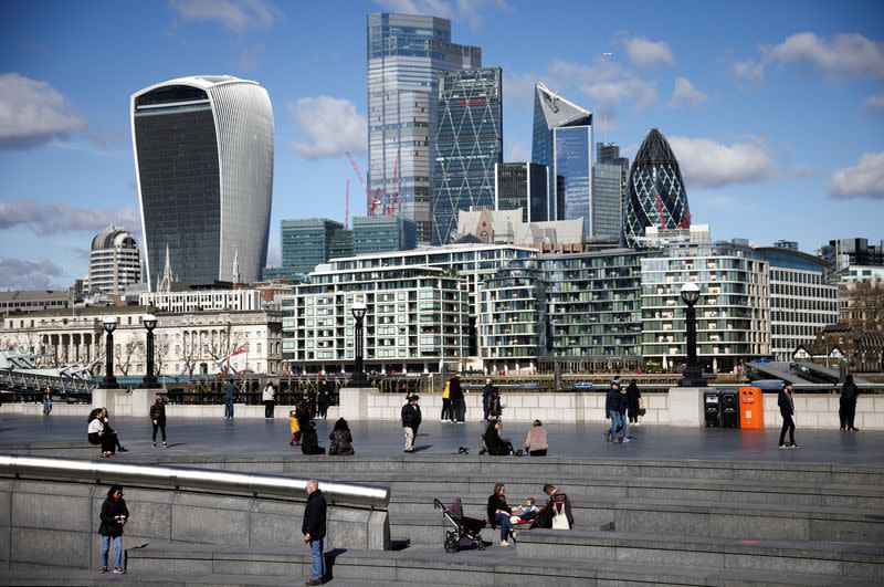 FILE PHOTO: The City of London financial district can be seen as people walk along the south side of the River Thames, amid the coronavirus disease (COVID-19) outbreak in London