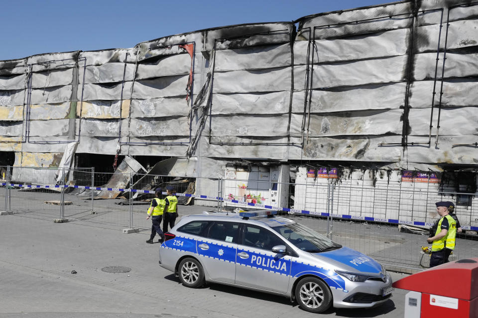 Police walks by a temporary fence put up to block access to a burnt-down shopping center in Warsaw, Poland, on Wednesday, May 15, 2024. A weekend fire at the Marywilska 44 shopping center dealt tragedy to many members of Poland's Vietnamese community. People lost entire livelihoods and say they don't know how they will manage to make a living. (AP Photo/Czarek Sokolowski)