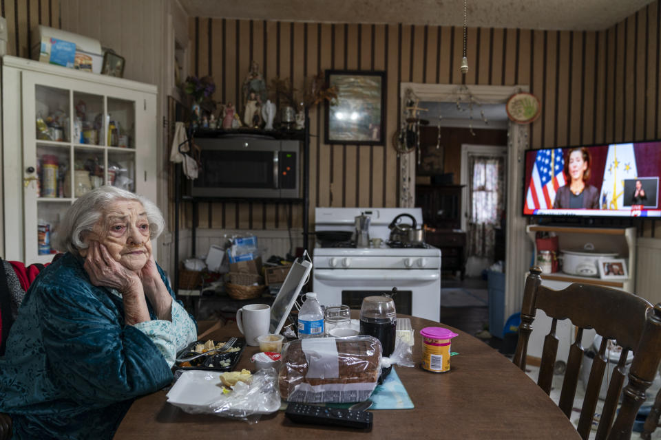 Rita Scanlon, 92, eats lunch delivered to her by Meals on Wheels of Rhode Island as she listens to Gov. Gina Raimondo's press conference urging residents to stay home for Thanksgiving amidst an increase in COVID hospitalizations, Wednesday, Nov. 25, 2020, in Central Falls, R.I. As more at-risk seniors find themselves unable to leave their homes during the pandemic, Meals on Wheels of Rhode Island has been delivering on average 4,000 meals per day up from their pre-pandemic average of 1,200. (AP Photo/David Goldman)