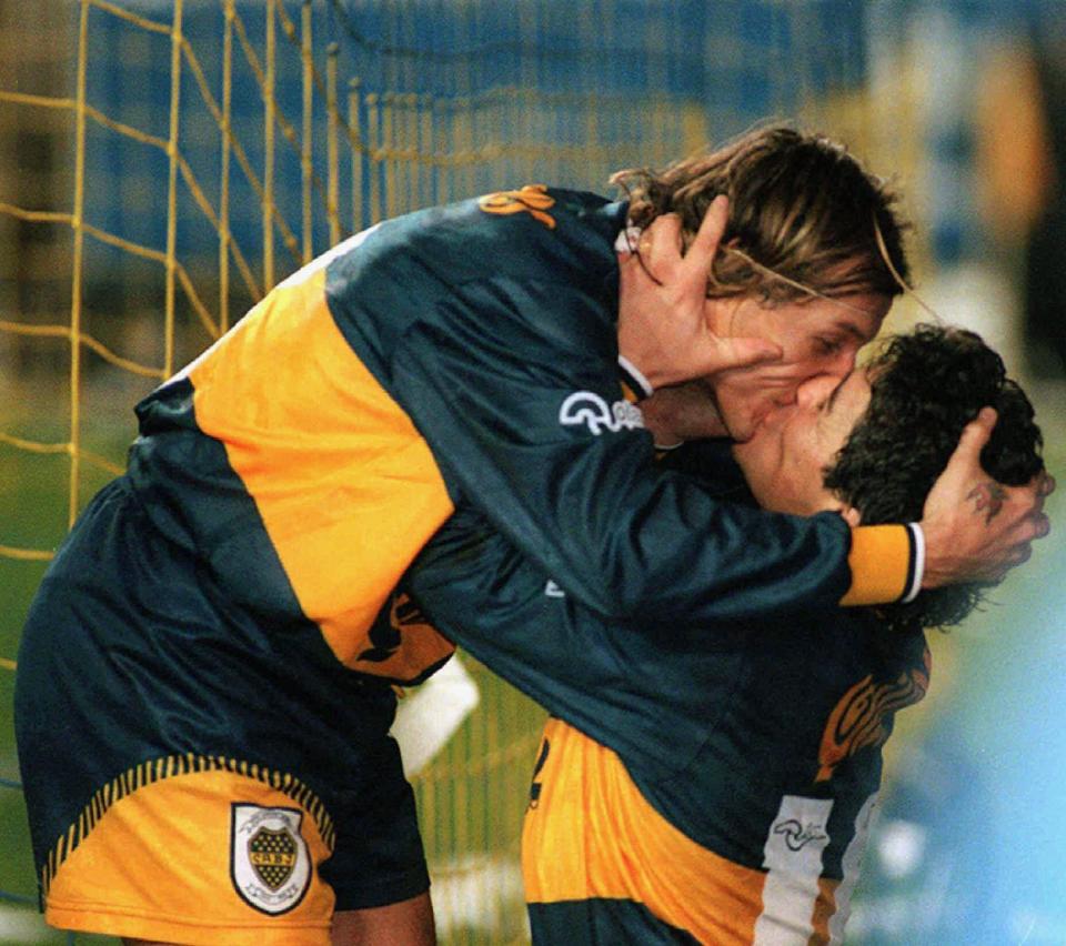 FILE - In this July 14, 1996 file photo released by Telam, Boca Juniors' Diego Maradona, right, and teammate Claudio Caniggia kiss as they celebrate Caniggia's goal, their team's second against River Plate, before their 4-1 victory in Buenos Aires, Argentina. The Argentine soccer great who was among the best players ever and who led his country to the 1986 World Cup title before later struggling with cocaine use and obesity, died from a heart attack on Wednesday, Nov. 25, 2020, at his home in Buenos Aires. He was 60. (Telam via AP File)