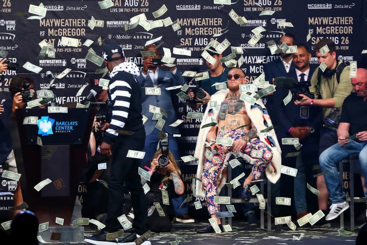 Floyd Mayweather (L) showered Conor McGregor in $1 bills in a bizarre and awkward news conference Thursday. (Getty)