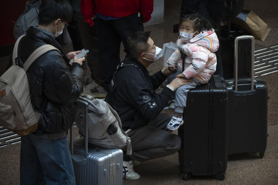 A child sits on a suitcase at Beijing West Railway Station in Beijing, Wednesday, Jan. 18, 2023. China in December lifted its strict "zero-COVID" policy, letting loose a wave of pent-up travel desire, particularly around China's most important time for family gatherings, referred to in China as the Spring Festival, that may be the only time in the year when urban workers return to their hometowns. (AP Photo/Mark Schiefelbein)