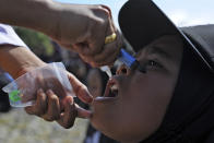 A girl receives drops of vaccine from a medical worker during a polio immunization campaign at Sigli Town Square in Pidie, Aceh province, Indonesia, Monday, Nov. 28, 2022. Indonesia has begun a campaign against the poliovirus in the the country's conservative province after several children were found infected with the highly-contagious disease that was declared eradicated in the country less than a decade ago. (AP Photo/Riska Munawarah)