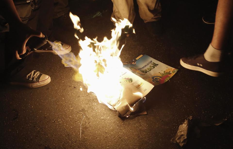 Demonstrators burn a 2014 World Cup sticker album during a protest in Sao Paulo May 24, 2014. The demonstrators rallied against the hosting of the World Cup in Brazil, and the costs associated with the sporting event. Activists are demanding more money be spent on education, health care, public transportation and to fight crime. REUTERS/Nacho Doce (BRAZIL - Tags: SPORT SOCCER CIVIL UNREST POLITICS WORLD CUP)