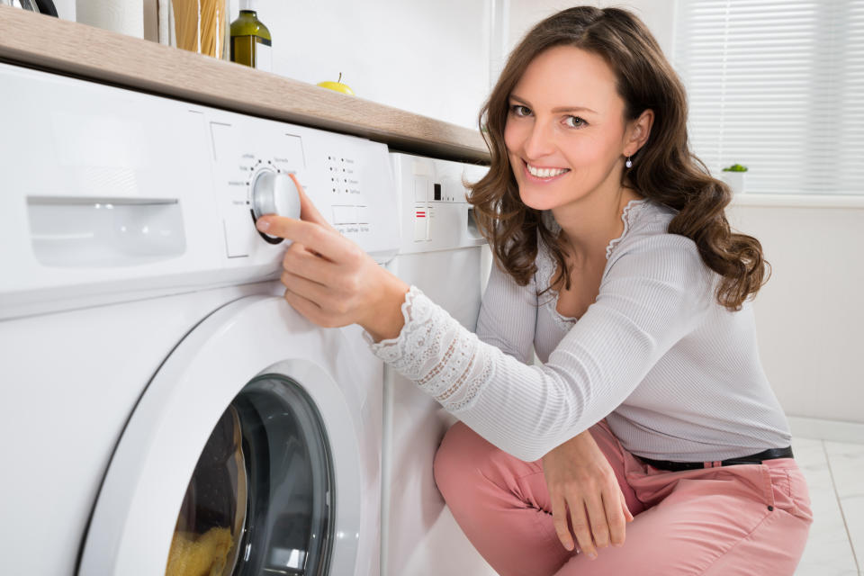 A young woman operates a laundry machine.