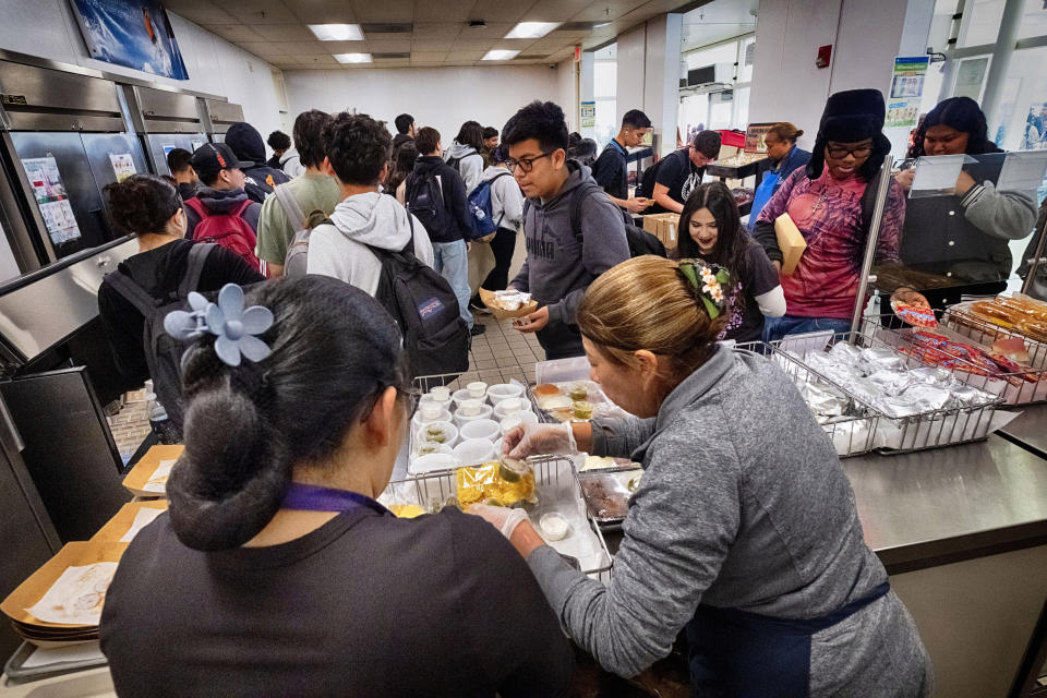 Cafeteria workers serve student lunches at Firebaugh High School in Lynwood, Calif. on Wednesday, April 3, 2024. Demand for school lunches has increased after California guaranteed free meals to all students regardless of their family's income. Now, districts are preparing to compete with the fast food industry for employees after a new law took effect guaranteeing a $20 minimum wage for fast food workers. (AP Photo/Richard Vogel)