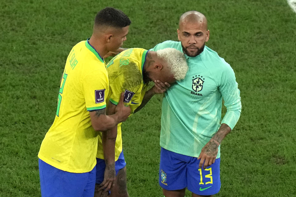 Brazil's Neymar, center, cries as he walks off the field with teammate Thiago Silva, left, and Brazil's Dani Alves after their loss in the World Cup quarterfinal soccer match against Croatia, at the Education City Stadium in Al Rayyan, Qatar, Friday, Dec. 9, 2022. (AP Photo/Alessandra Tarantino)