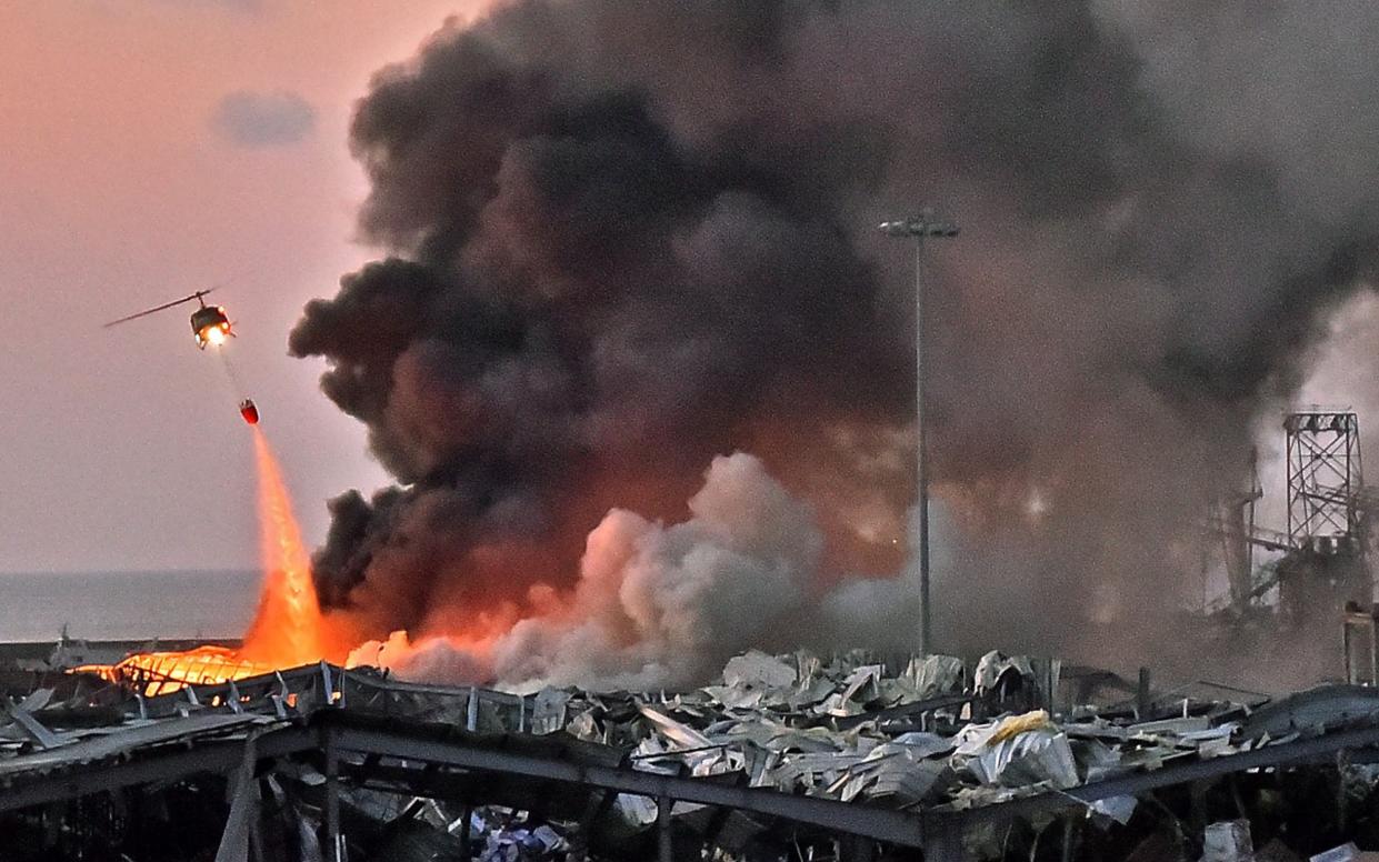 A helicopter puts out a fire at the scene of an explosion at the Beirut port - STR/AFP