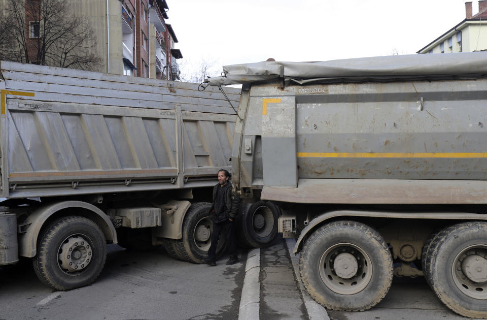 A man passes by a barricade made of trucks loaded with stones on a street in northern, Serb-dominated part of ethnically divided town of Mitrovica, Kosovo, Wednesday, Dec. 28, 2022. Serbs have erected more roadblocks in northern Kosovo and defied international demands to remove those placed earlier. (AP Photo/Bojan Slavkovic)