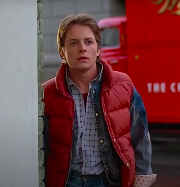 Marty McFly wearing sneakers, jeans, a button-up, a jean jacket, and a vest