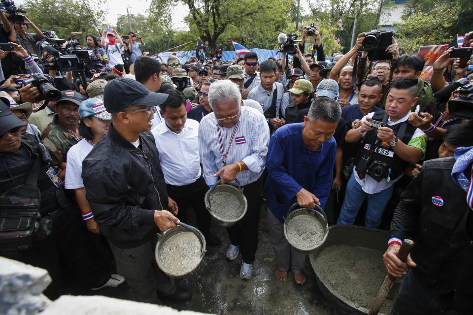 Anti-government protest leader Suthep prepares to pour cement to block a gate of the Government House during a rally in Bangkok