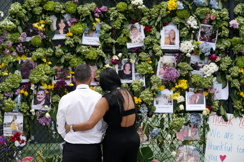 People stand near a make-shift memorial outside St. Joseph Catholic Church near the Champlain Towers South residential condo, Tuesday, June 29, 2021, in Surfside, Fla. Many people were still unaccounted for after Thursday's fatal collapse. (AP Photo/Gerald Herbert)