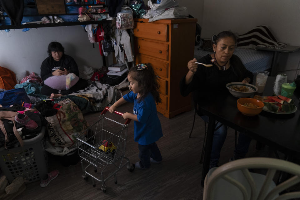 Deneffy Sánchez, izquierda, observa su smartphone en una litera en la que duerme con su madre, Lilian López, derecha, y su hermana, Jennifer, en un apartamento tipo estudio que comparten con otras personas, el sábado 9 de septiembre de 2023, en Los Ángeles. La pérdida de empleos durante la pandemia de COVID-19, aunada al alza en las rentas, ha obligado a muchos residentes de California como López y su familia a aceptar condiciones de vivienda desesperadas. (AP Foto/Jae C. Hong)