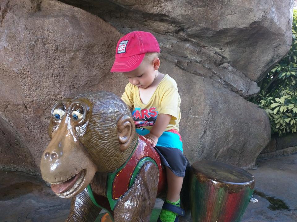 toddler sitting on a toy monkey statue at universal port of entry