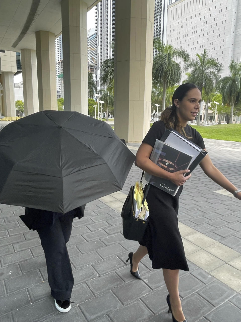 Celebrity handbag designer Nancy Gonzalez hides under an umbrella as she walks with her lawyer Andrea Lopez outside the federal courthouse Monday, April 22, 2024, in Miami. The Colombian designer, whose bags were purchased by celebrities like Britney Spears and the cast of the "Sex and the City" TV series, was sentenced to 18 months in federal prison on Monday for leading a smuggling ring that illegally imported into the U.S. crocodile handbags for sale at high end showrooms using couriers on commercial flights. (AP Photo/Josh Goodman)