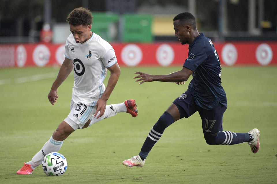 Minnesota United midfielder Hassani Dotson, left, controls a ball in front of Sporting Kansas City midfielder Gadi Kinda during the first half of an MLS soccer match Sunday, July 12, 2020, in Kissimmee, Fla. (AP Photo/Phelan M. Ebenhack)