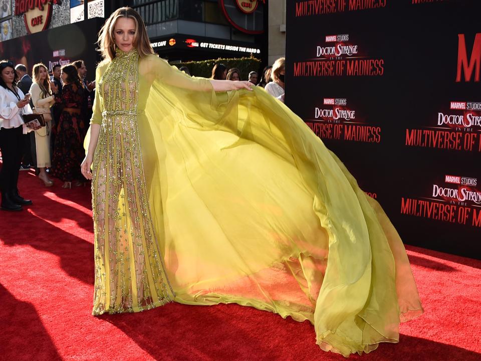 Rachel McAdams wears a lime green yellow jumpsuit with a flowing cape at the red carpet of "Doctor Strange in the Multiverse of Madness" in May 2022.