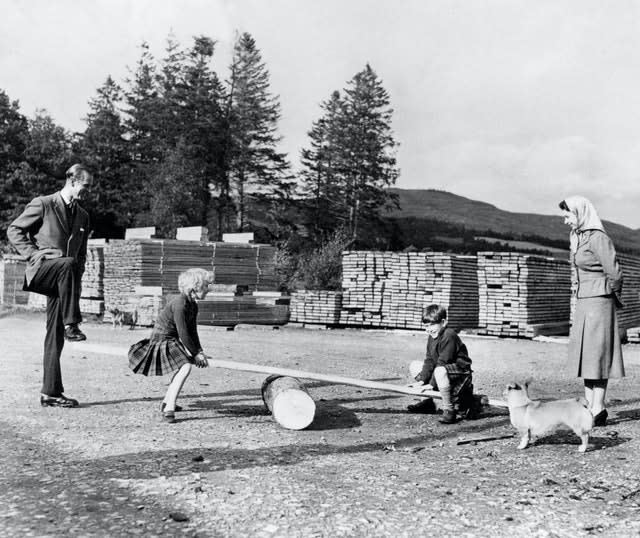 Prince Charles and Princess Anne, watched by the Queen and the Duke of Edinburgh, play on a see-saw made from a log and a plank of wood on the Balmoral Estate in 1957