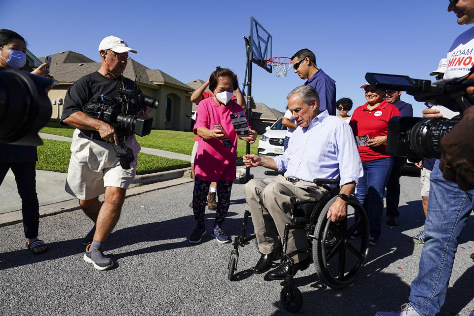 Victoria Rafols talks with Texas Gov. Greg Abbott Saturday, Oct. 1, 2022, as Abbott visits people at home in Harlingen, Texas, ahead of early voting for his campaign. (Denise Cathey/The Brownsville Herald via AP)