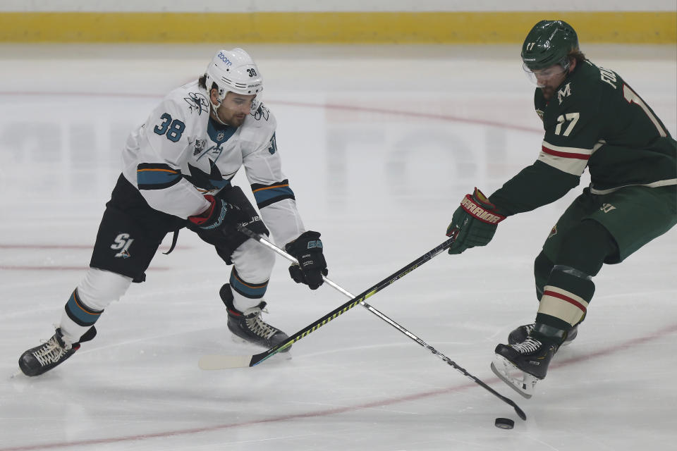 Minnesota Wild's Marcus Foligno (17) and San Jose's Mario Ferraro (38) go after the puck in the first period of an NHL hockey game Sunday, Jan. 24, 2021, in St. Paul, Minn. (AP Photo/Stacy Bengs)