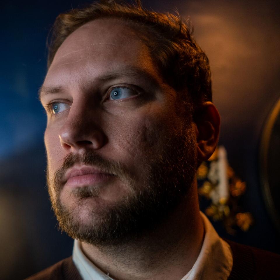 Man looking away from the camera, outside at a window